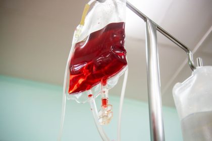Bolsa de sangue conectada a um equipo intravenoso em ambiente clínico.