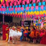 Dançarinos participam de uma celebração brasileira colorida, cercados por enfeites festivos.