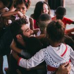 Grupo de pessoas se abraça durante uma reunião comunitária em Vila Sarapuí, no Brasil.