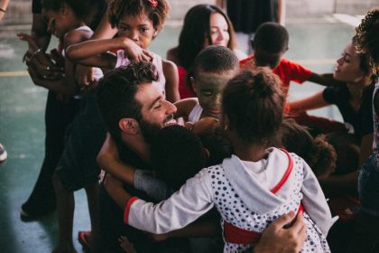 Grupo de pessoas se abraça durante uma reunião comunitária em Vila Sarapuí, no Brasil.
