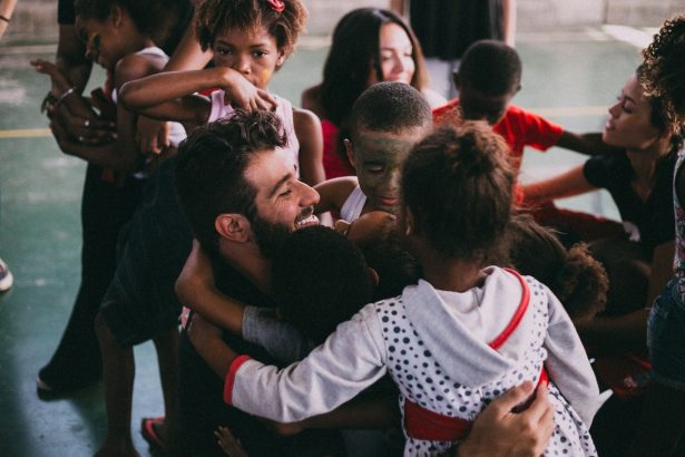 Grupo de pessoas se abraça durante uma reunião comunitária em Vila Sarapuí, no Brasil.