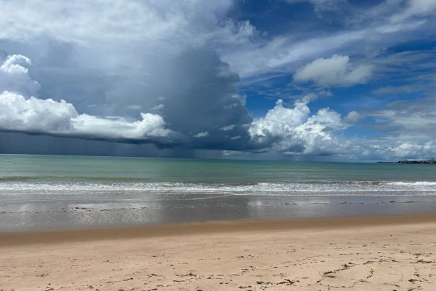 Praia de Tambaú, no Brasil, com ondas e nuvens carregadas sobre o litoral.